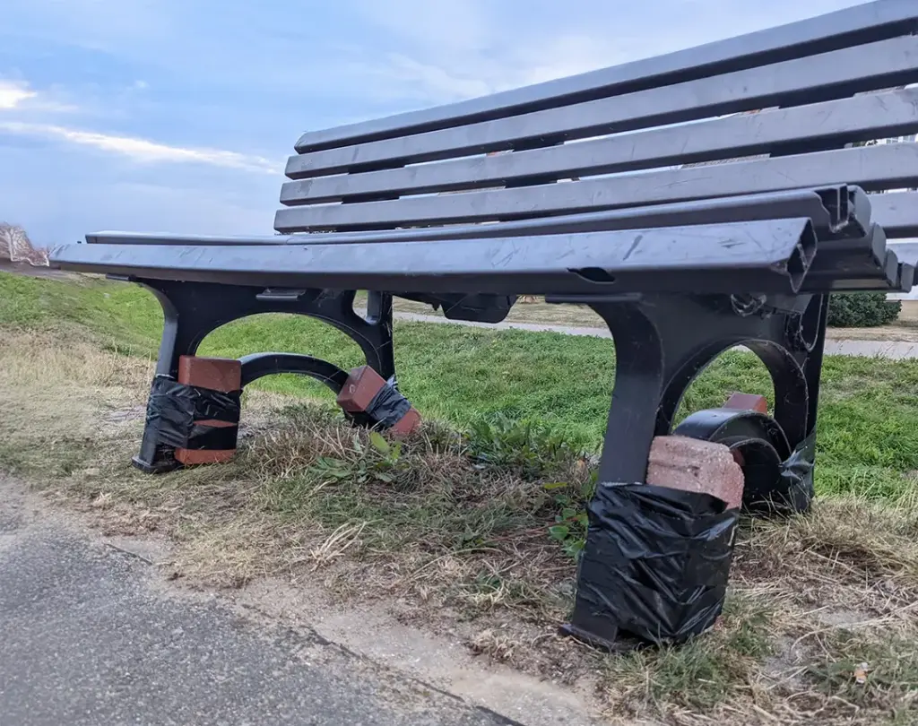 Steinen sichern mithilfe von Gaffer-Tape eine Bank gegen den Wind