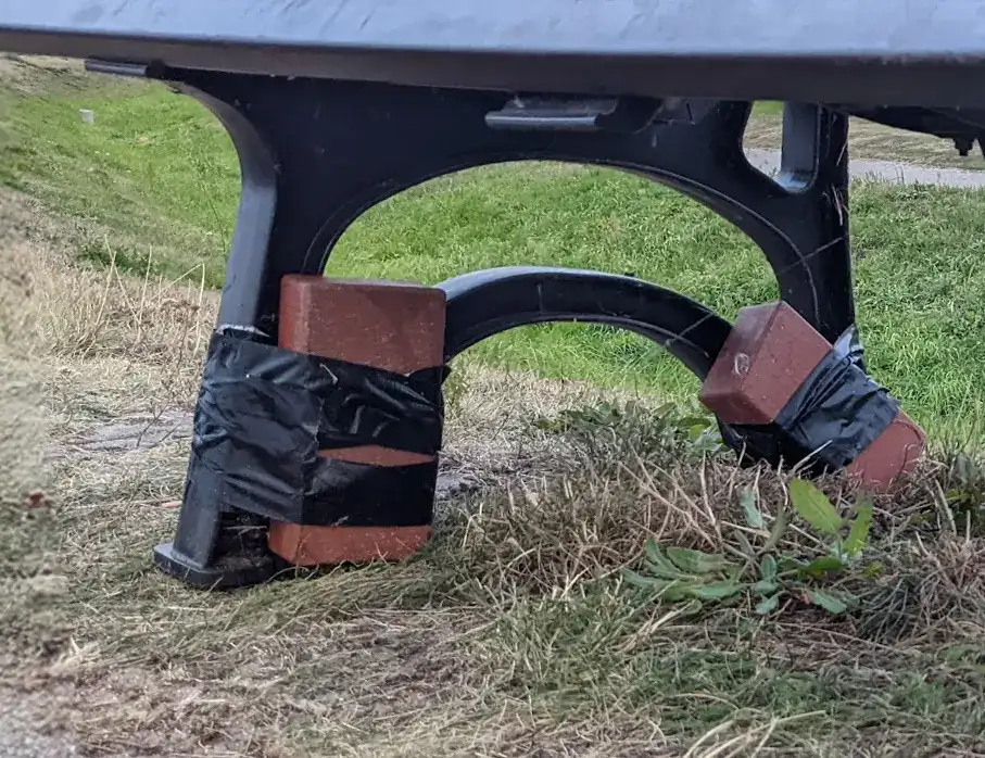 Steinen sichern mithilfe von Gaffer-Tape eine Bank gegen den Wind